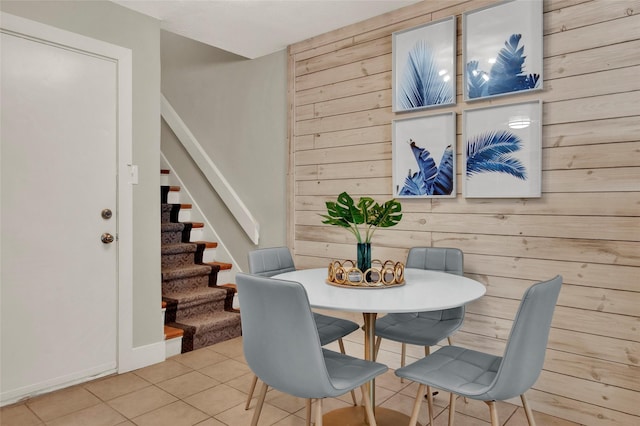 tiled dining area with wood walls and stairs