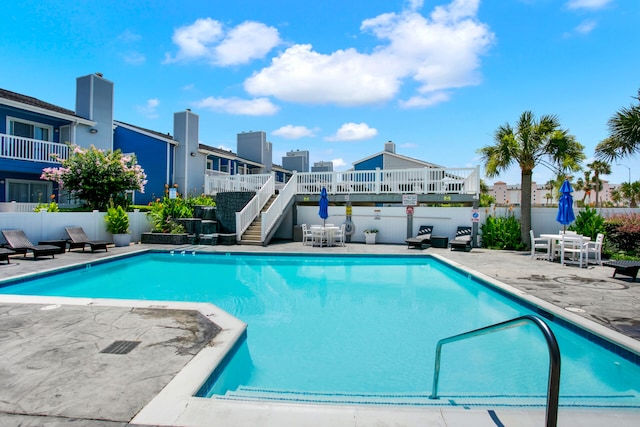 pool with stairway, a patio area, fence, and a wooden deck