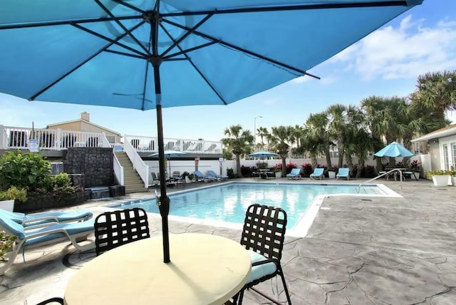 pool with a patio, stairway, and outdoor dining area