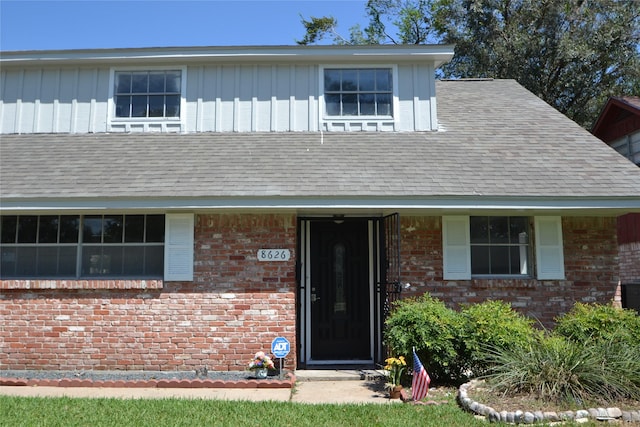 view of front of house with brick siding, board and batten siding, and a shingled roof