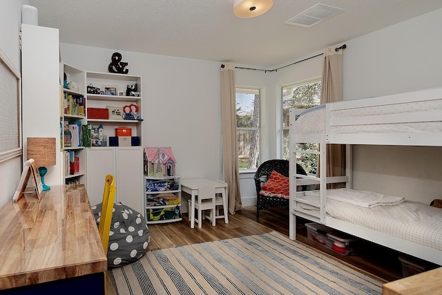 bedroom featuring wood finished floors, visible vents, and a textured ceiling