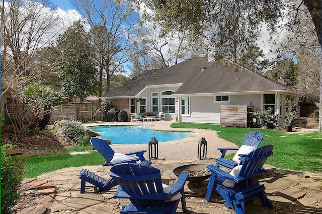 outdoor pool featuring fence, a fire pit, a lawn, and a patio area