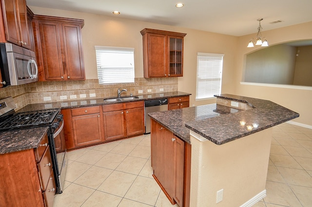 kitchen with appliances with stainless steel finishes, light tile patterned flooring, a sink, and a notable chandelier