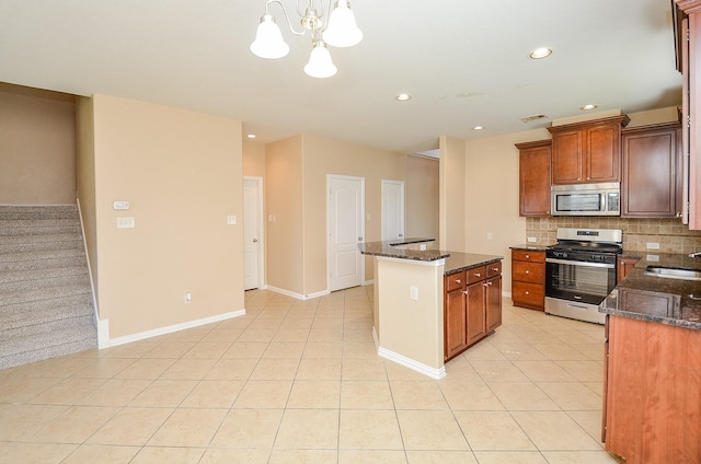 kitchen with light tile patterned floors, stainless steel appliances, backsplash, a sink, and a kitchen island