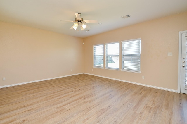 unfurnished room featuring light wood-style floors, baseboards, visible vents, and a ceiling fan