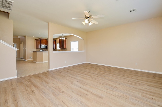 unfurnished living room with light wood finished floors, baseboards, visible vents, and ceiling fan with notable chandelier