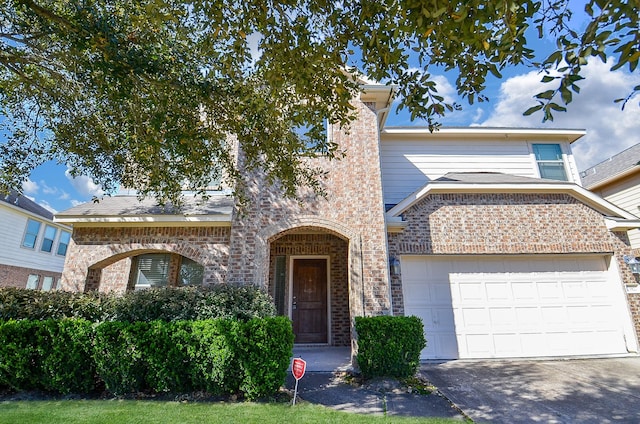 traditional-style home featuring an attached garage, concrete driveway, and brick siding