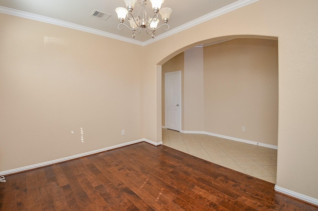 unfurnished room featuring hardwood / wood-style flooring, visible vents, arched walkways, and crown molding