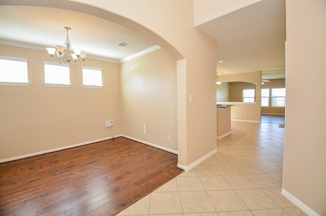 spare room with light tile patterned floors, visible vents, arched walkways, and crown molding