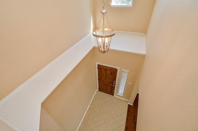 foyer entrance with light tile patterned floors, a towering ceiling, and an inviting chandelier