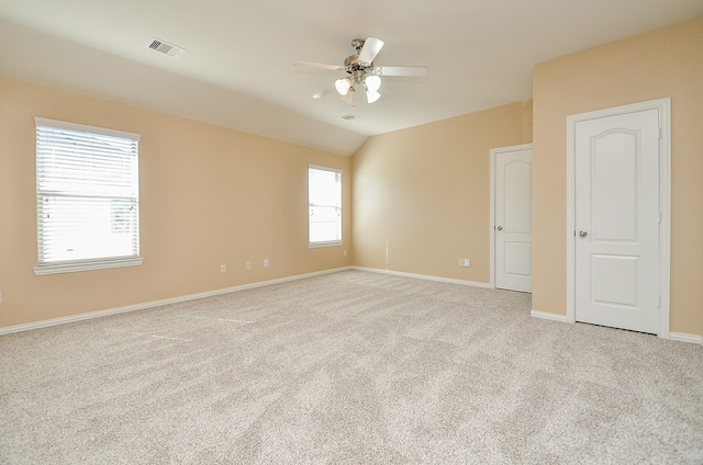 unfurnished room featuring lofted ceiling, visible vents, light carpet, ceiling fan, and baseboards