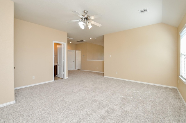 spare room featuring light carpet, baseboards, visible vents, and vaulted ceiling