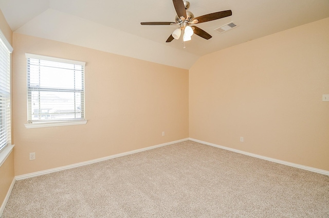 carpeted empty room featuring lofted ceiling, ceiling fan, visible vents, and baseboards