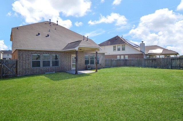 rear view of property featuring brick siding, a yard, and a fenced backyard