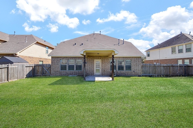 rear view of property featuring brick siding, a fenced backyard, a patio area, and a yard