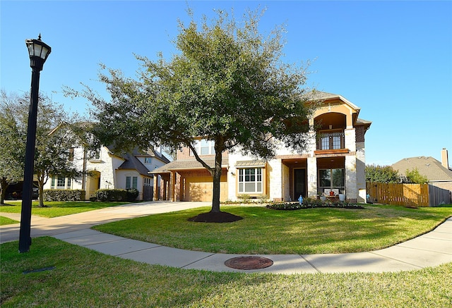 view of front of home featuring concrete driveway, a front yard, fence, and a balcony