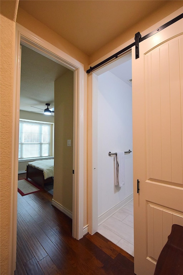 corridor with baseboards, hardwood / wood-style floors, and a barn door