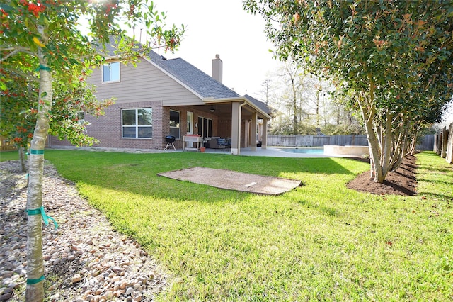 rear view of house with a chimney, a patio area, brick siding, and a fenced backyard