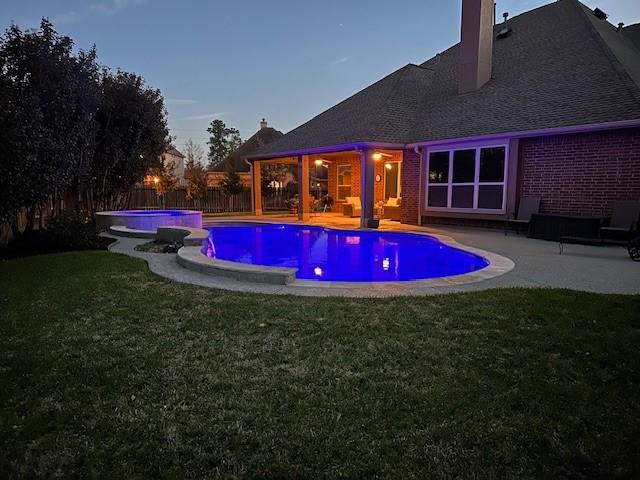 view of pool with a pool with connected hot tub, a fenced backyard, a lawn, and a patio