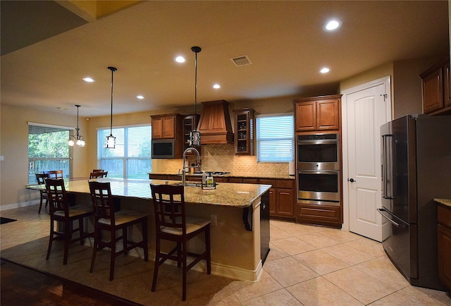 kitchen featuring custom exhaust hood, visible vents, backsplash, appliances with stainless steel finishes, and a sink