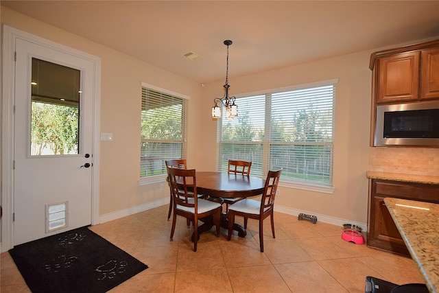 dining area with light tile patterned floors, an inviting chandelier, visible vents, and baseboards