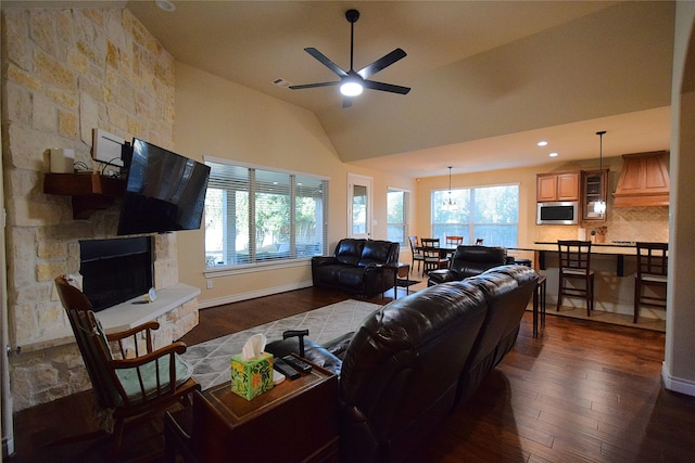 living room featuring dark wood-style floors, a fireplace, a ceiling fan, vaulted ceiling, and baseboards