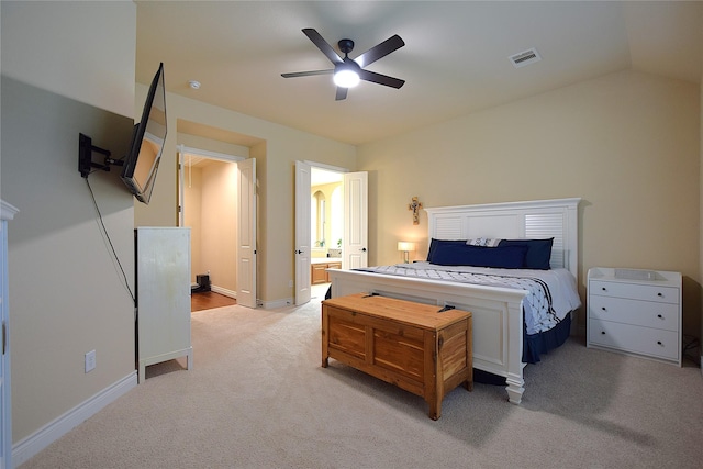 bedroom with baseboards, visible vents, connected bathroom, light colored carpet, and vaulted ceiling