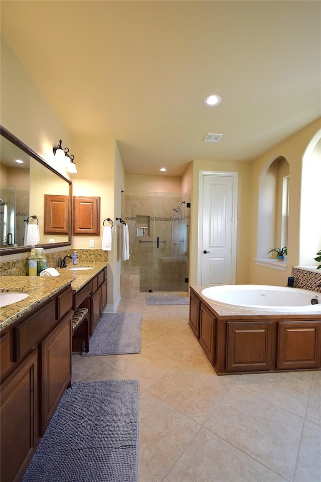 full bathroom with double vanity, a stall shower, visible vents, a garden tub, and a sink