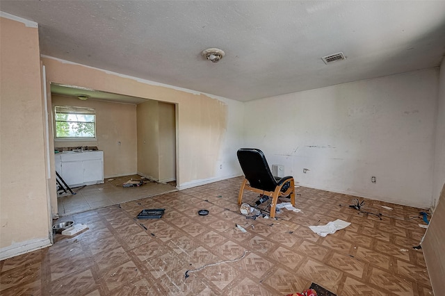 interior space featuring baseboards, visible vents, and a textured ceiling