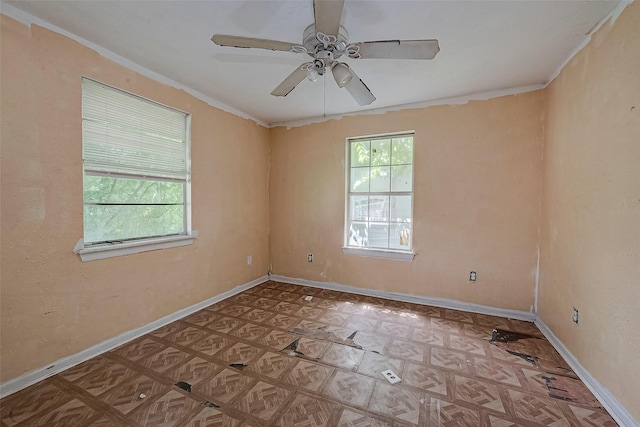 spare room with a ceiling fan, plenty of natural light, and baseboards