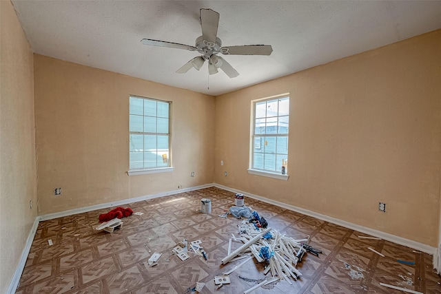 spare room with a textured ceiling, a ceiling fan, and baseboards