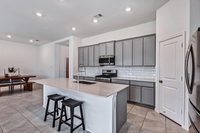 kitchen with appliances with stainless steel finishes, gray cabinets, visible vents, and a sink