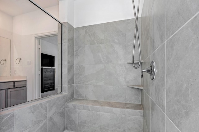 full bath featuring tiled shower and vanity