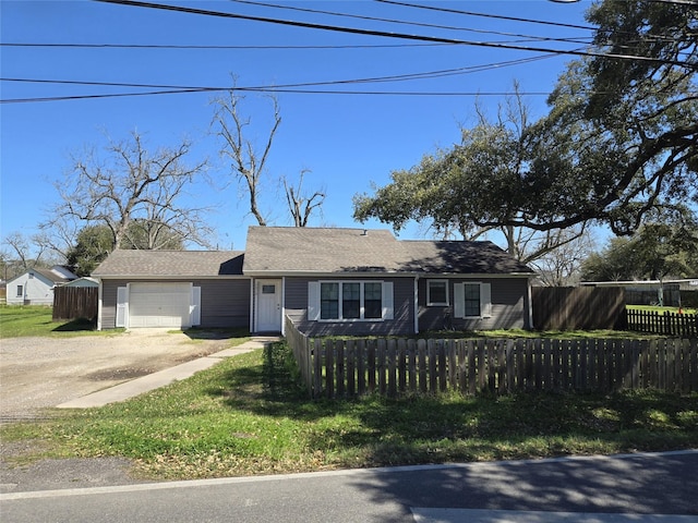 ranch-style home featuring dirt driveway, a fenced front yard, and a garage