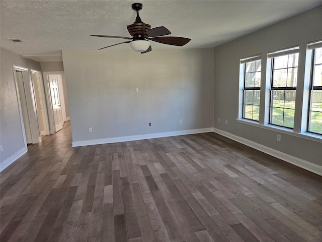 spare room featuring visible vents, dark wood-type flooring, ceiling fan, a textured ceiling, and baseboards