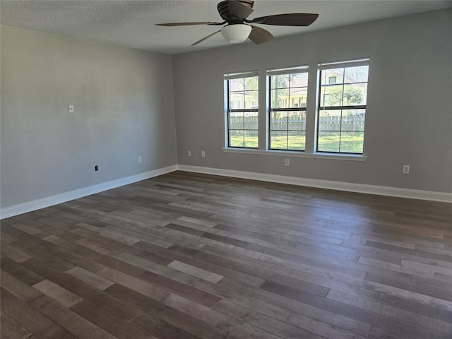 spare room with a ceiling fan, baseboards, dark wood finished floors, and a textured ceiling