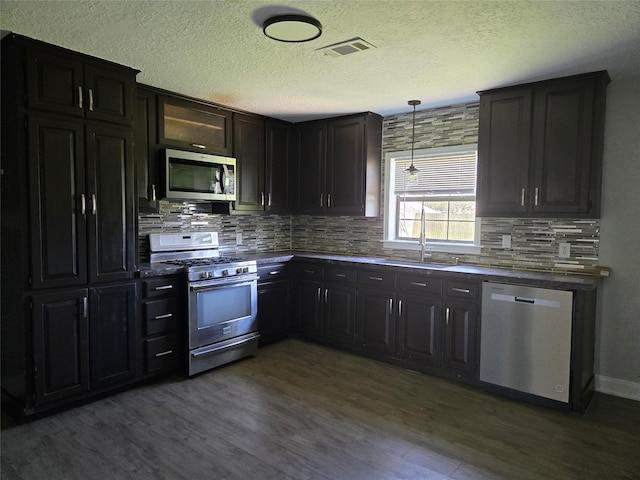 kitchen featuring stainless steel appliances, visible vents, a sink, and dark wood-type flooring