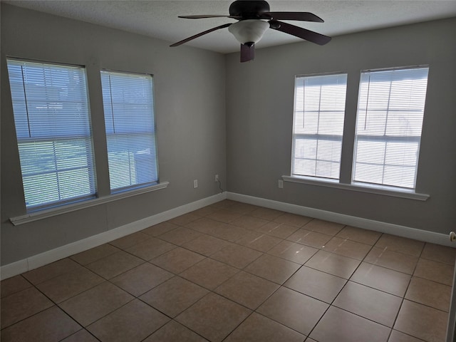 empty room with ceiling fan, a textured ceiling, and baseboards