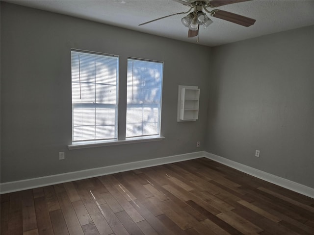 empty room with dark wood finished floors, a textured ceiling, baseboards, and ceiling fan