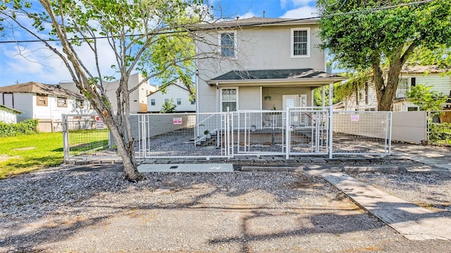 view of front of house with a porch, a fenced front yard, a gate, and stucco siding