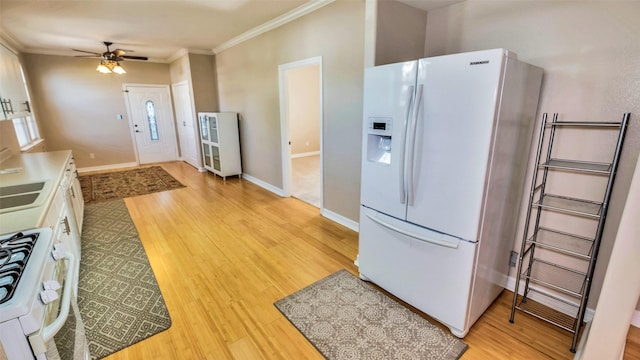 kitchen featuring light wood-type flooring, white appliances, crown molding, and baseboards