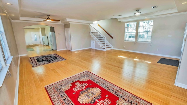 living area featuring arched walkways, wood finished floors, visible vents, stairway, and crown molding