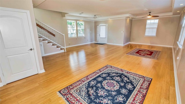 foyer entrance featuring stairway, ornamental molding, ceiling fan, wood finished floors, and baseboards