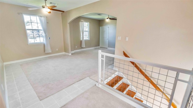 unfurnished room featuring carpet, arched walkways, visible vents, baseboards, and tile patterned floors