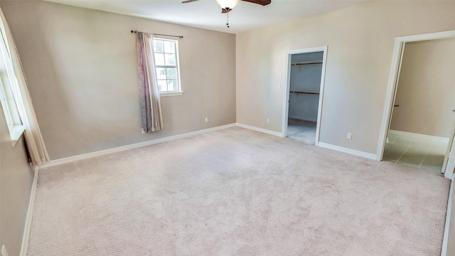 unfurnished bedroom featuring a closet, a spacious closet, carpet flooring, ceiling fan, and baseboards