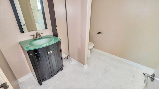 bathroom featuring toilet, tile patterned flooring, vanity, and baseboards