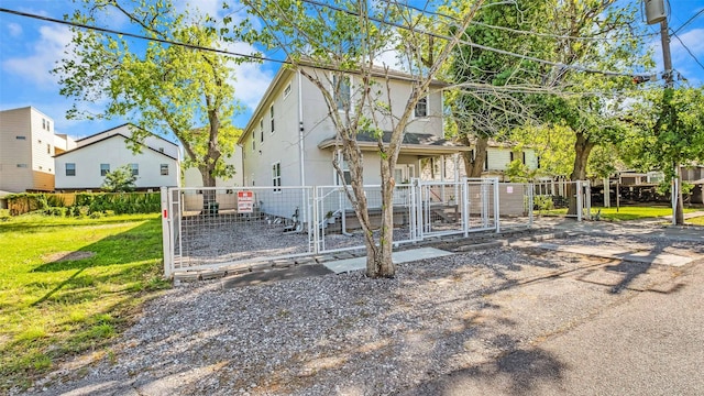 rear view of property featuring a gate, fence, a lawn, and stucco siding