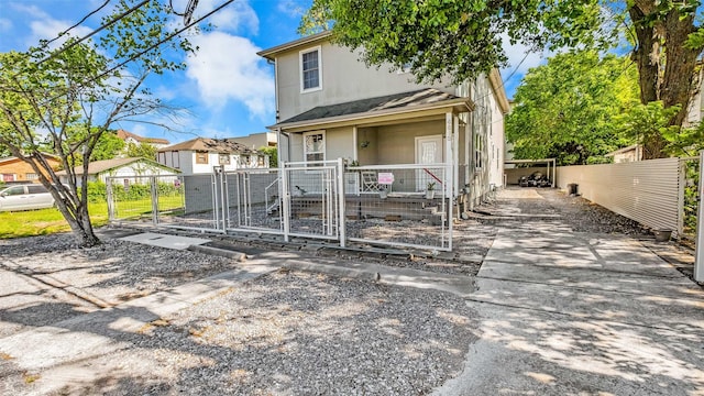 view of front of house featuring covered porch, a fenced front yard, a gate, and stucco siding