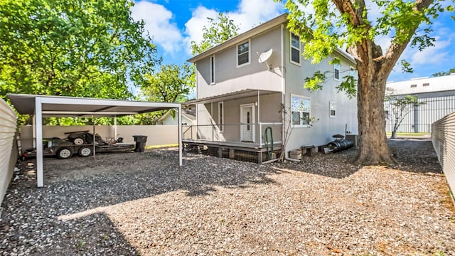 back of property featuring a carport, gravel driveway, and fence