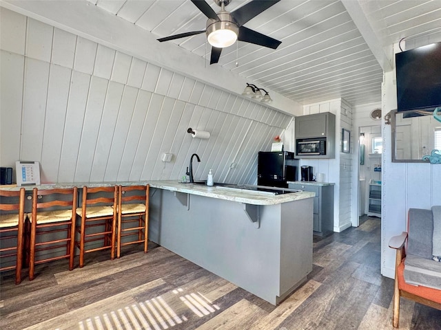 310 Angel Wing St, Surfside Beach, TX 77541 - kitchen with a breakfast bar, beam ceiling, black appliances, and wood finished floors